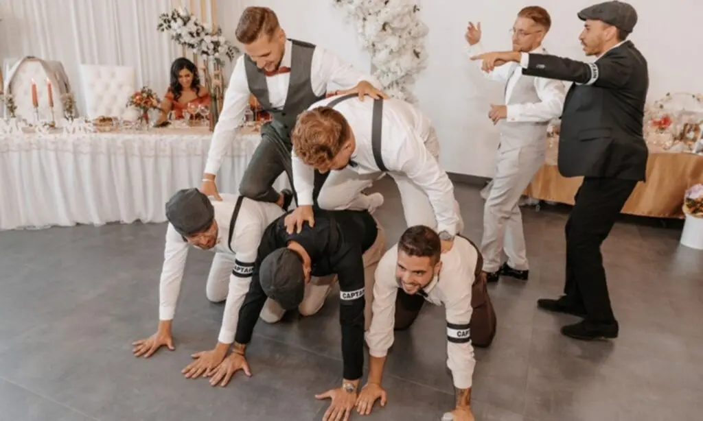 Bräutigam und Cousins bauen beim Hochzeitsspiel eine Menschenpyramide - WeddingBro Events Bräutigam und Cousins bauen beim Hochzeitsspiel eine Menschenpyramide