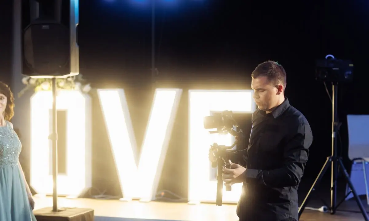 Videograf Valeri Galerie 1 - WeddingBro Events Videograf Valeri filmt bei einer Hochzeitsfeier vor leuchtenden Buchstaben
